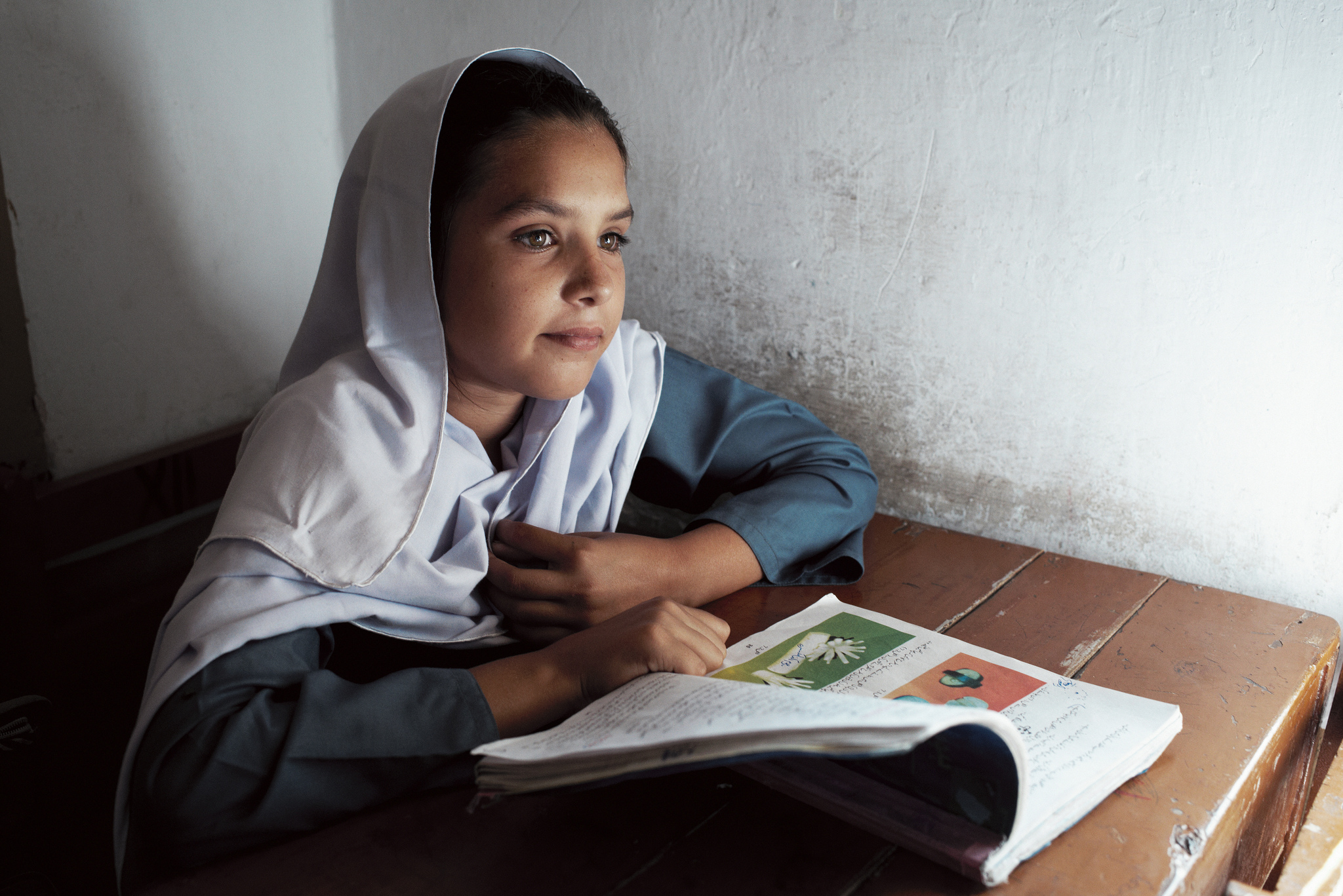 Rimsha Farooq, élève de niveau 6, devant son livre pendant un cours à l'école Khinger Khurd, dans la province du Pendjab, au Pakistan. Septembre 2012. Crédit STARS/Kristian Buus
